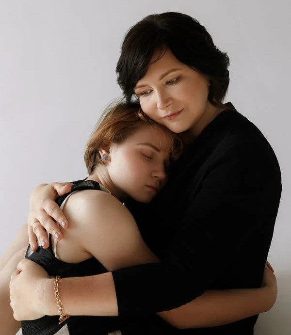 A women with dark hair embracing a young lady with blonde hair